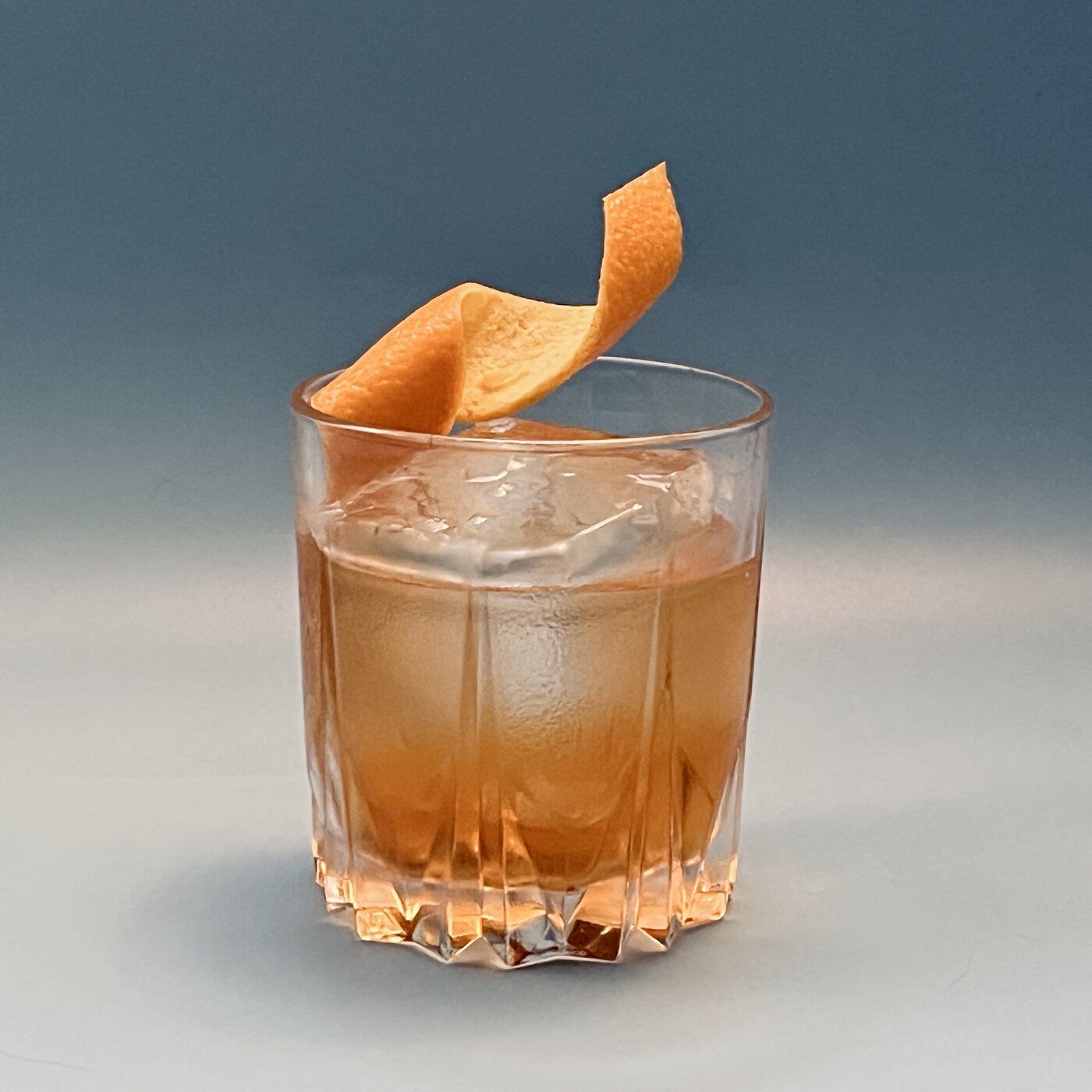 Finished cocktail with citrus and clear ice.