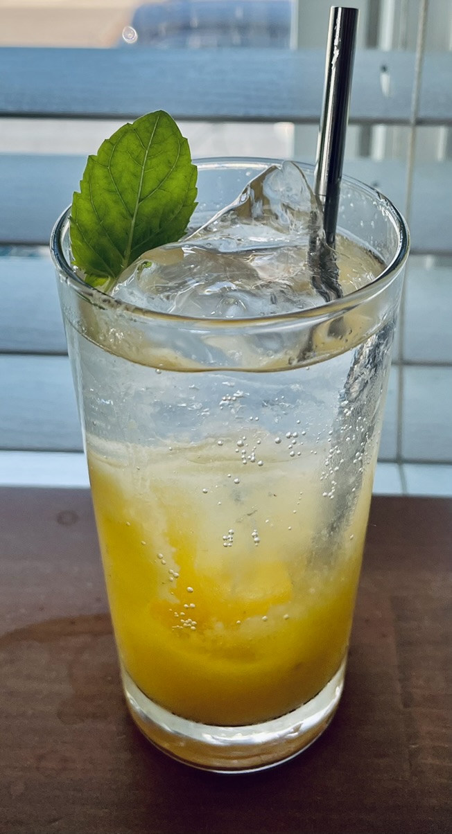 Bright citrus highball with clear ice and fresh basil garnish