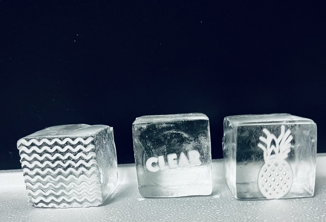 Three specialty clear ice cubes with stamped and branded designs