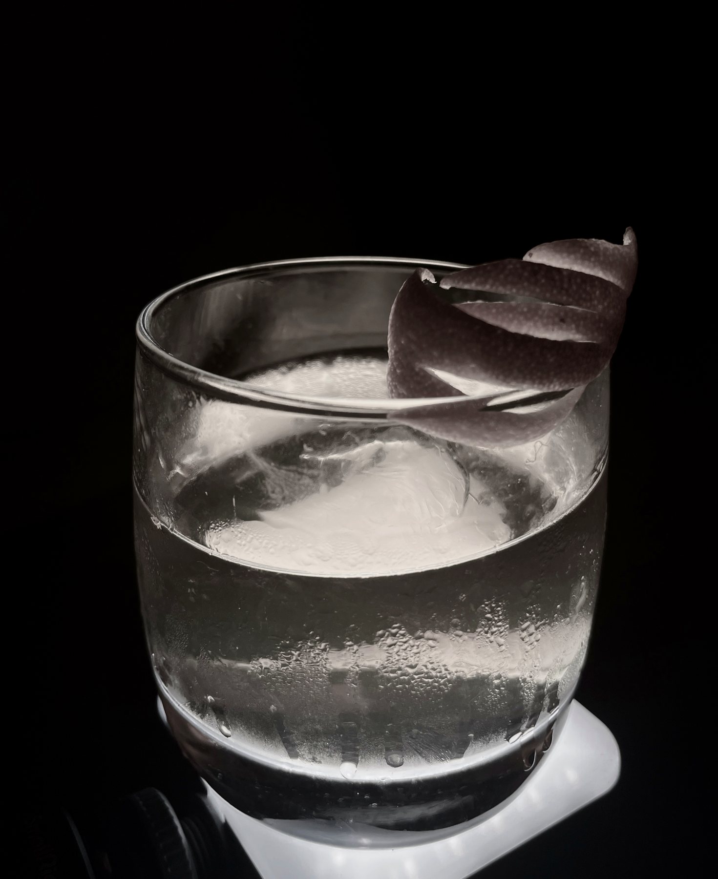 Crystal clear ice in a rocks glass against a dark background