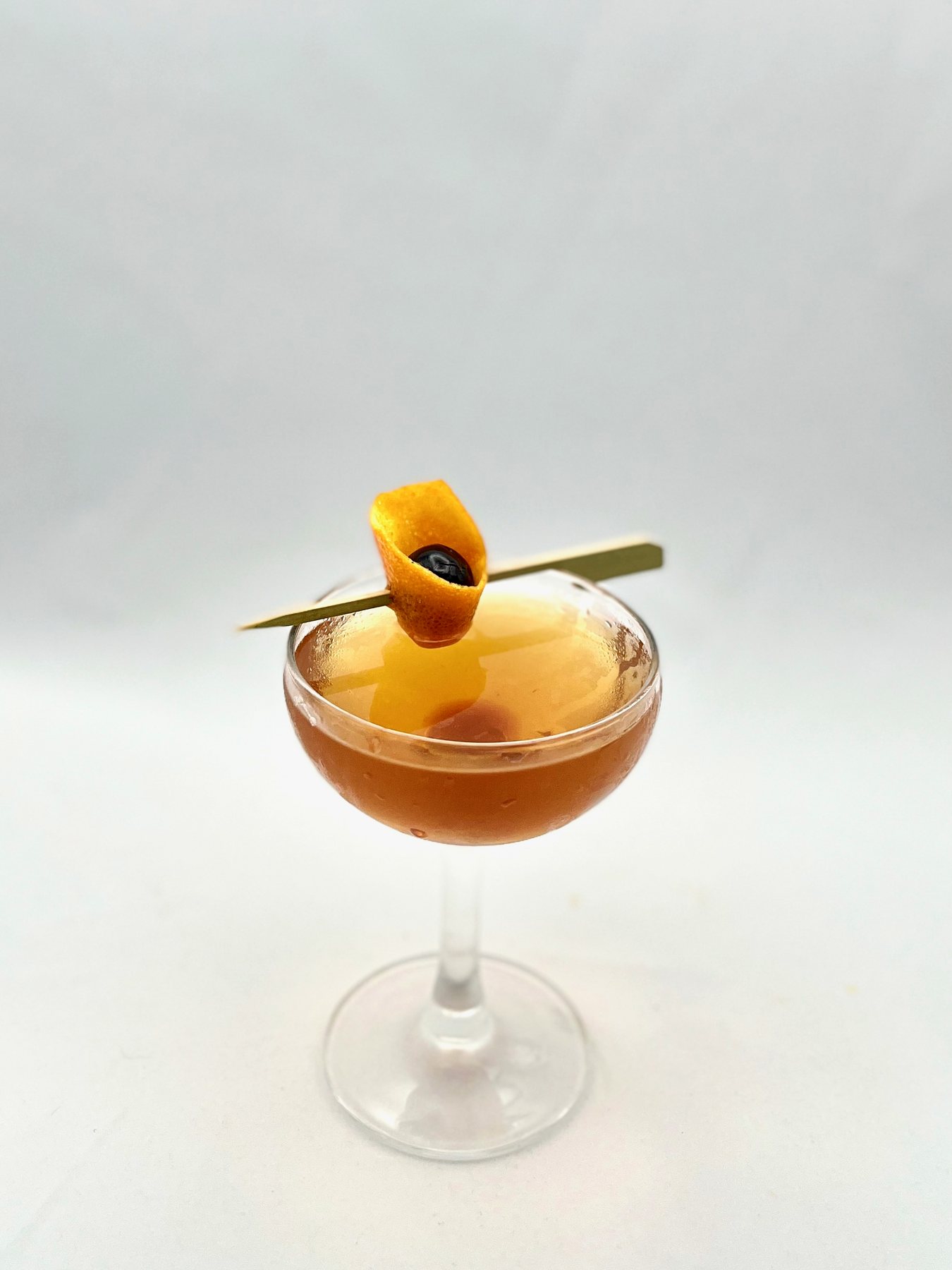 Golden coupe cocktail with orange peel garnish