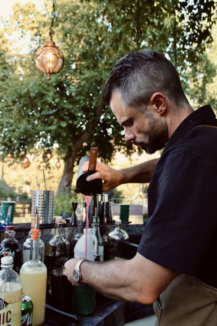 Joe Willeford pouring a cocktail at an outdoor private event bar
