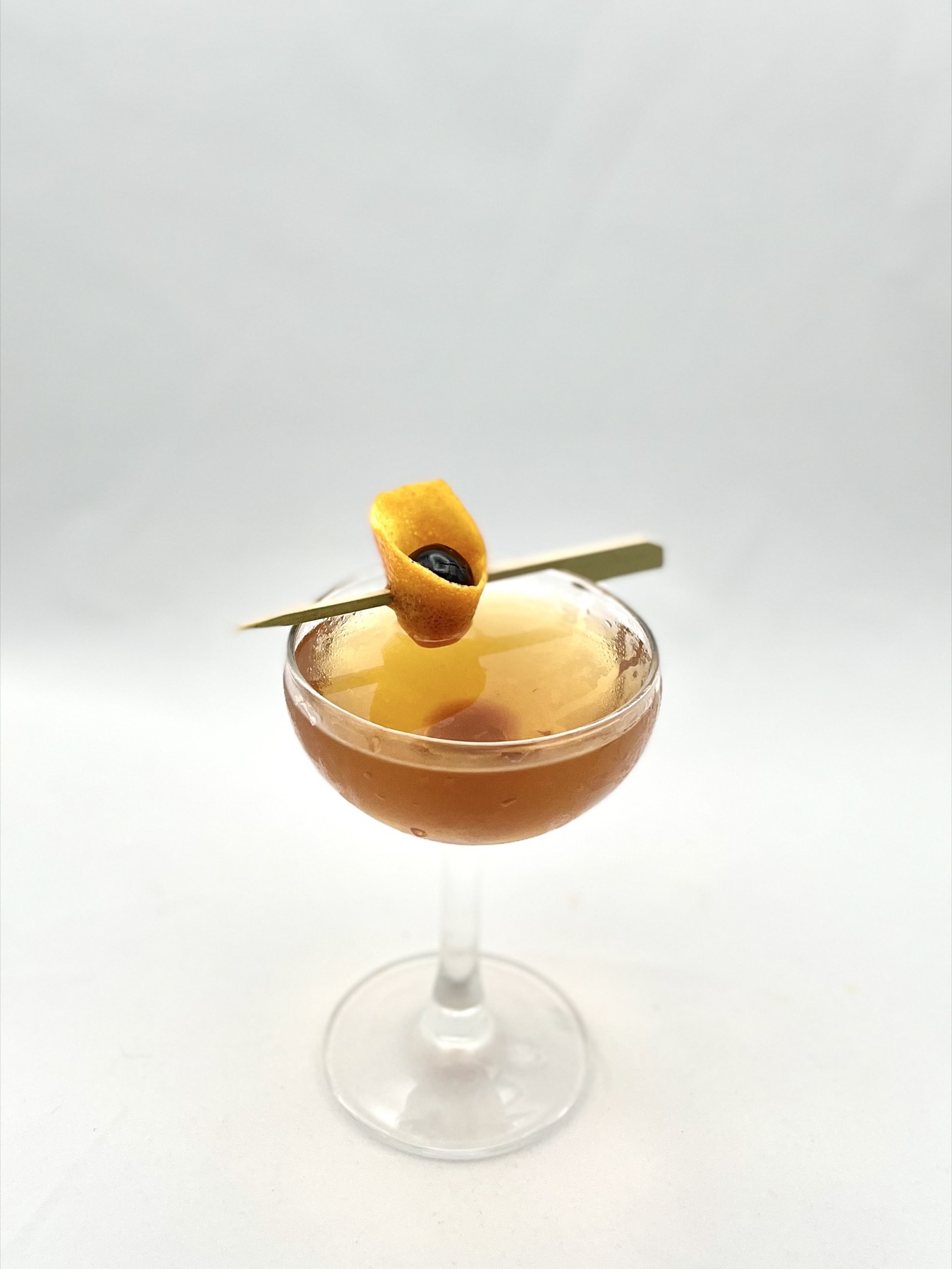 Manhattan-style cocktail served up with citrus garnish