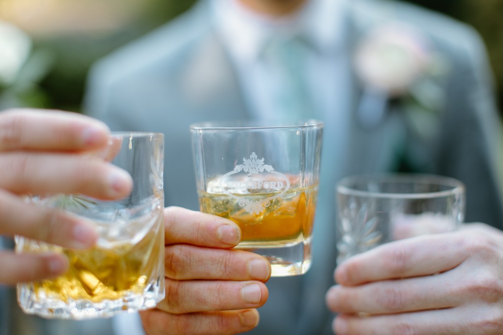 Wedding guests toasting with rocks glasses over clear ice and premium spirits